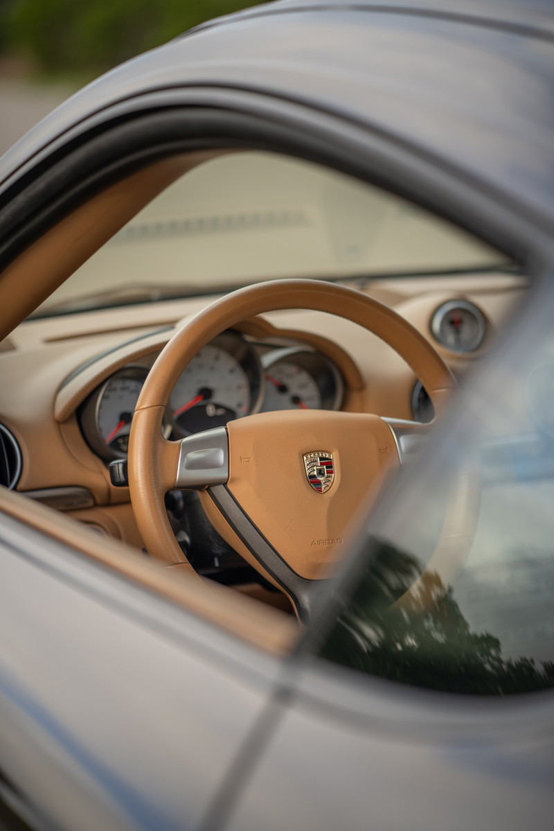 Interior view of a tan 2008 Porsche Cayman S with a tan steering wheel and dashboard.