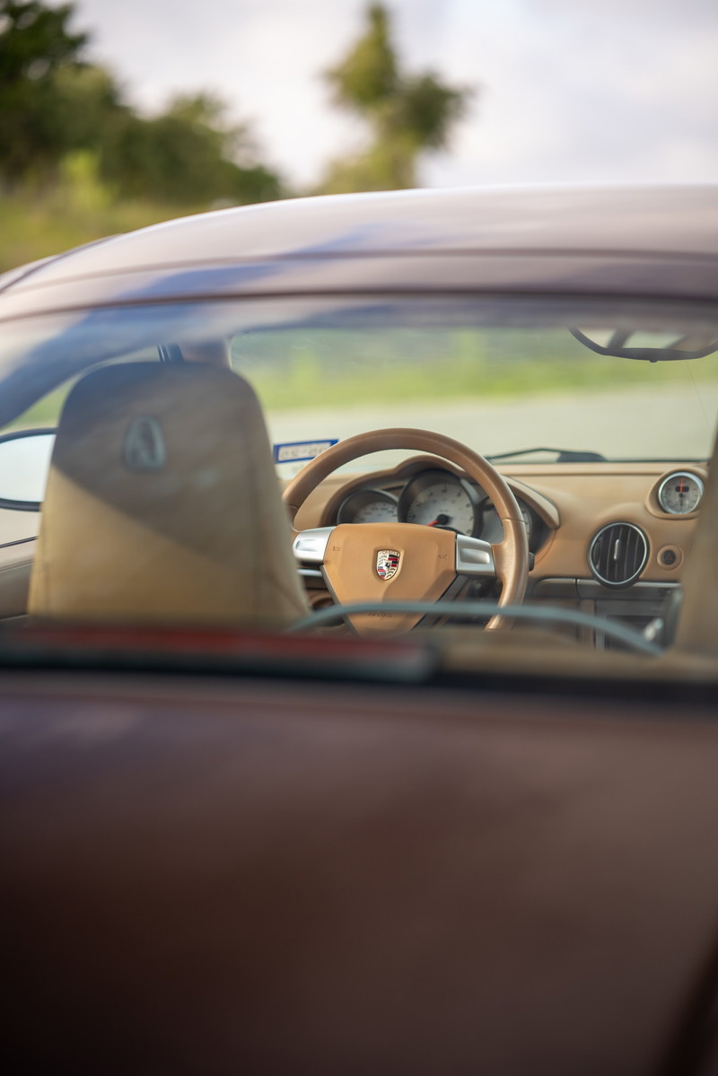 2008 Porsche Cayman S interior with tan leather trim and chrome accents on the steering wheel.