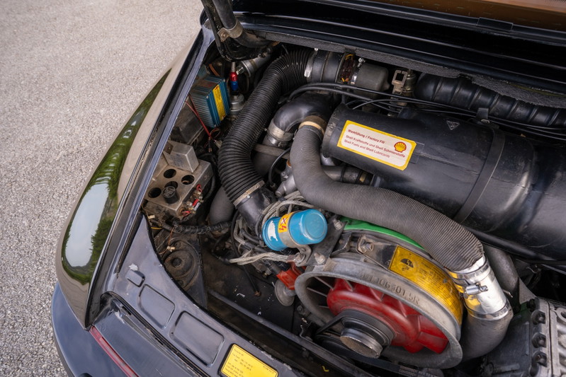 Close-up of a black 1976 Porsche 911S Sportomatic engine bay with a blue oil cooler.