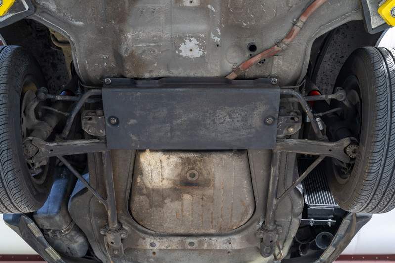 Underbody of a black 1976 Porsche 911S Sportomatic showing rear suspension and exhaust.
