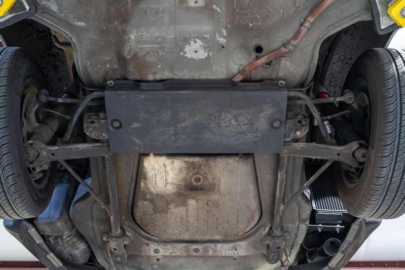 Underbody of a black 1976 Porsche 911S Sportomatic showing rear suspension and exhaust.