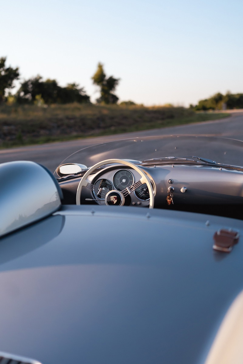 1955 Porsche 550 Spyder dashboard with white steering wheel, classic gauges, and grey body trim.