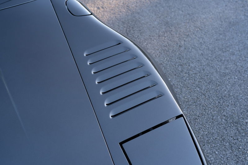 Close up on dark grey 1989 Porsche 930 Turbo Flachbau hood vents and headlight.