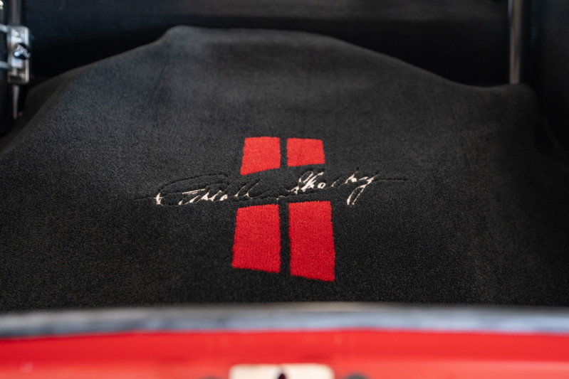 Black floor mat with red Shelby Cobra emblem and signature in a red 1965 Superformance Shelby Daytona Coupe.