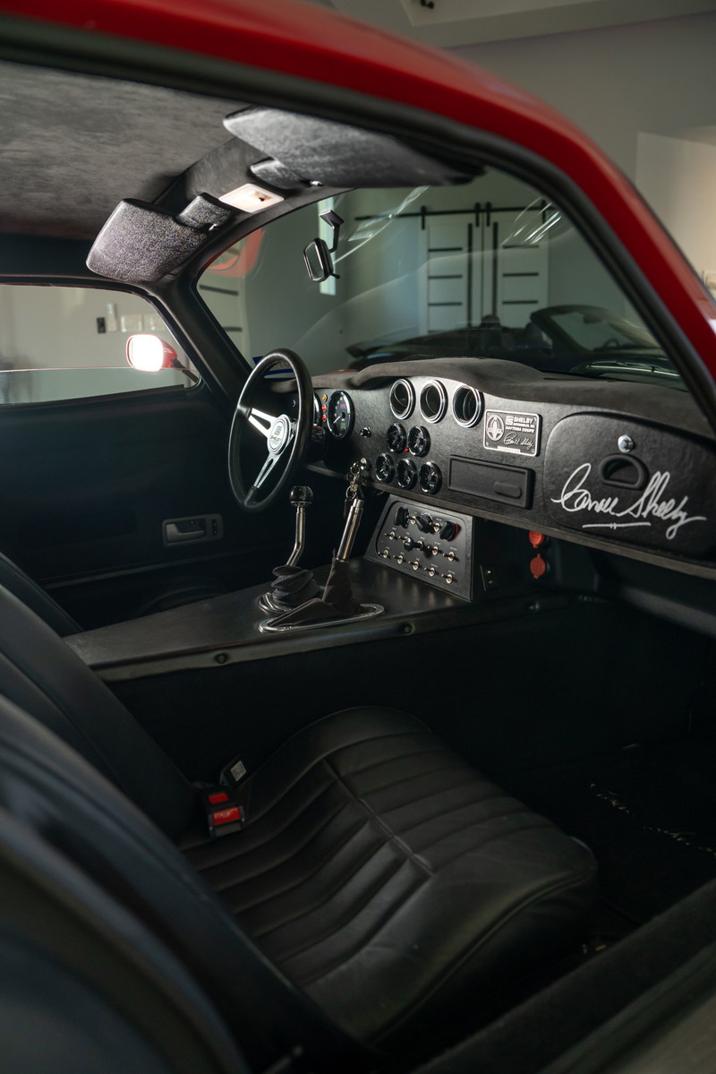 Red 1965 Superformance Shelby Daytona CSX interior with a leather seat, shifter, and signed dashboard.
