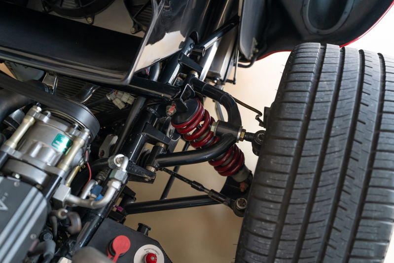Close-up of a red 1965 Superformance Shelby Daytona CSX tire and suspension system.