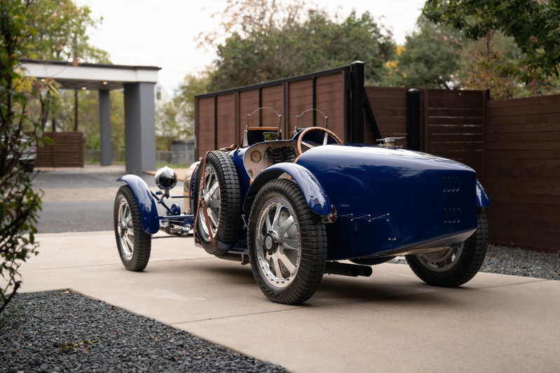 Rear view of a blue 1927 Pur Sang Bugatti Type 35 with wire-spoke rims and dual spare tires.