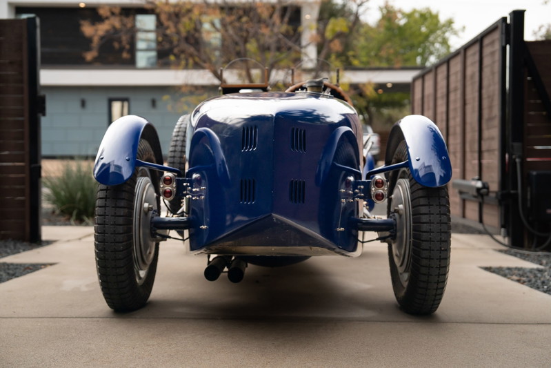 Rear view of a vintage blue 1927 Pur-Sang Bugatti Type 35 with spoked rims and a polished grille.