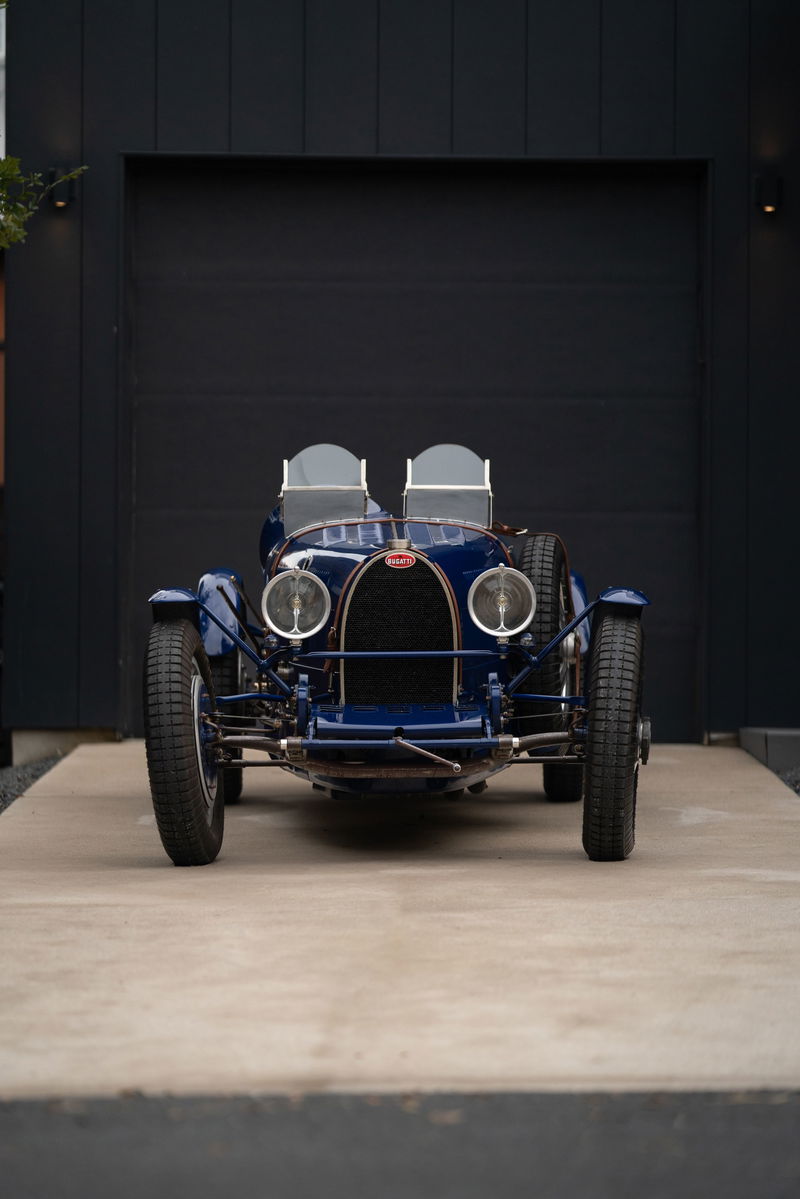 Front view of a dark blue 1927 Bugatti Type 35 Pur Sang with dual windscreens and wire-spoke wheels.