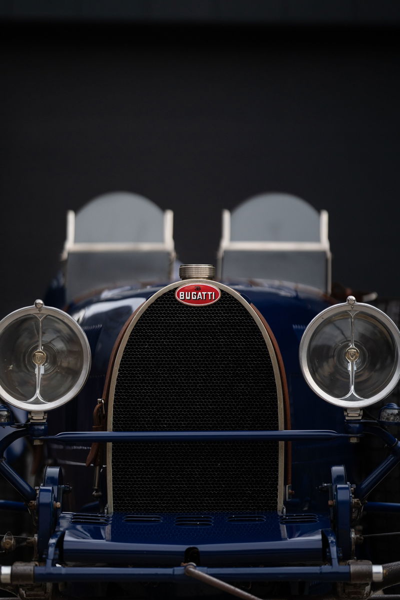 Front view of a vintage blue Bugatti Type 35, showing the iconic grille, headlights, and Bugatti emblem.