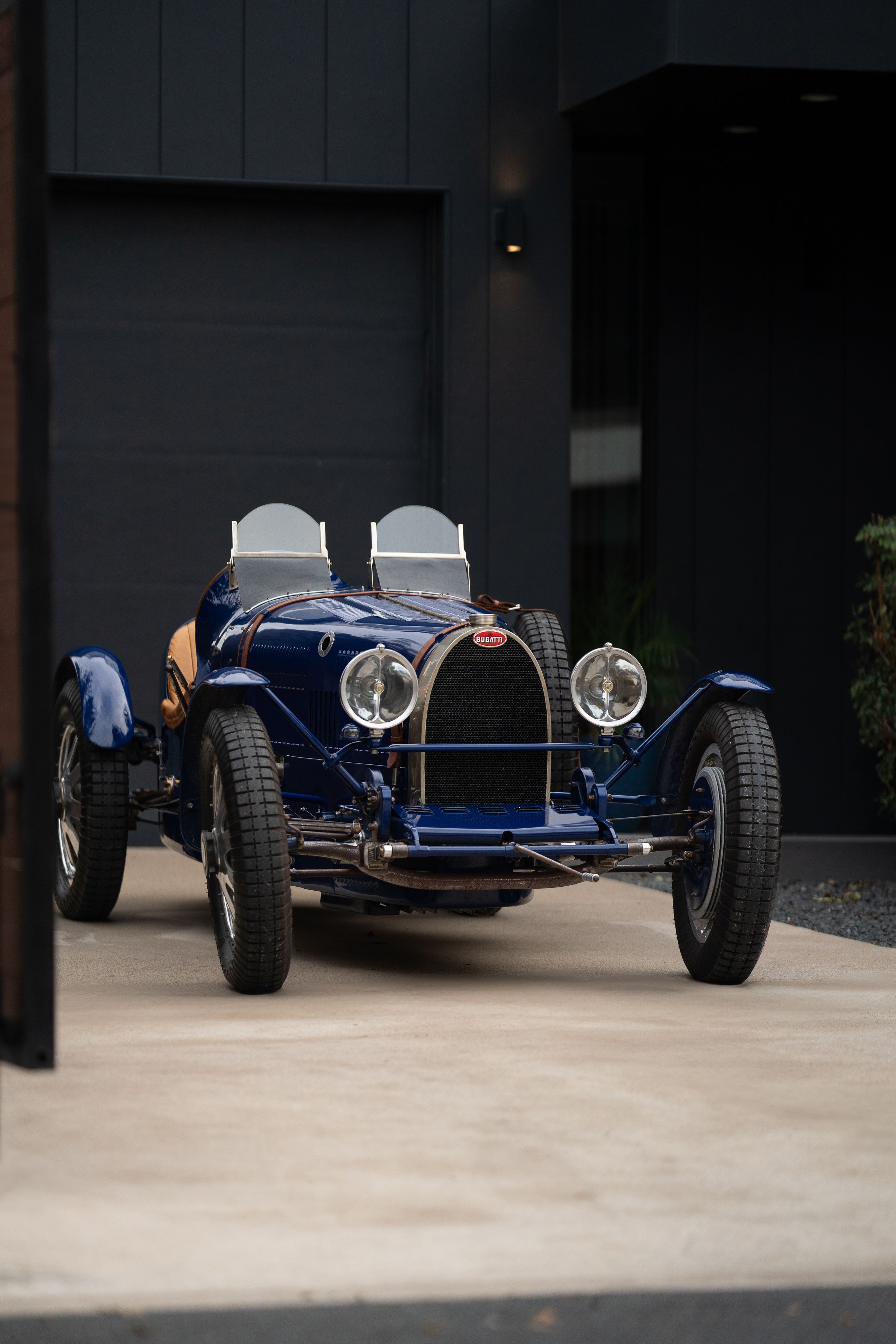 Blue 1927 Bugatti Type 35 Pur Sang open-top roadster with chrome rims and dual windscreens.