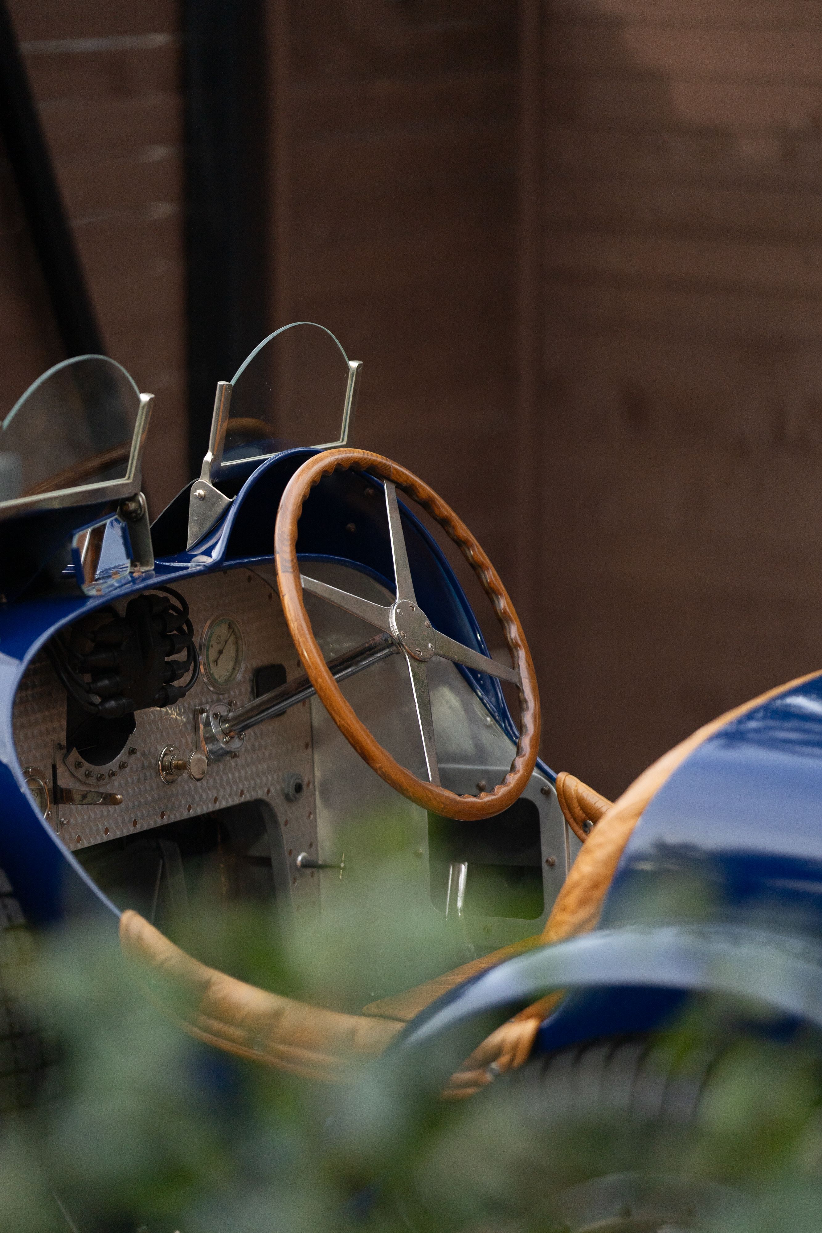 Close-up of a vintage blue 1927 Pur Sang Bugatti Type 35 cockpit with wood-rimmed steering wheel.