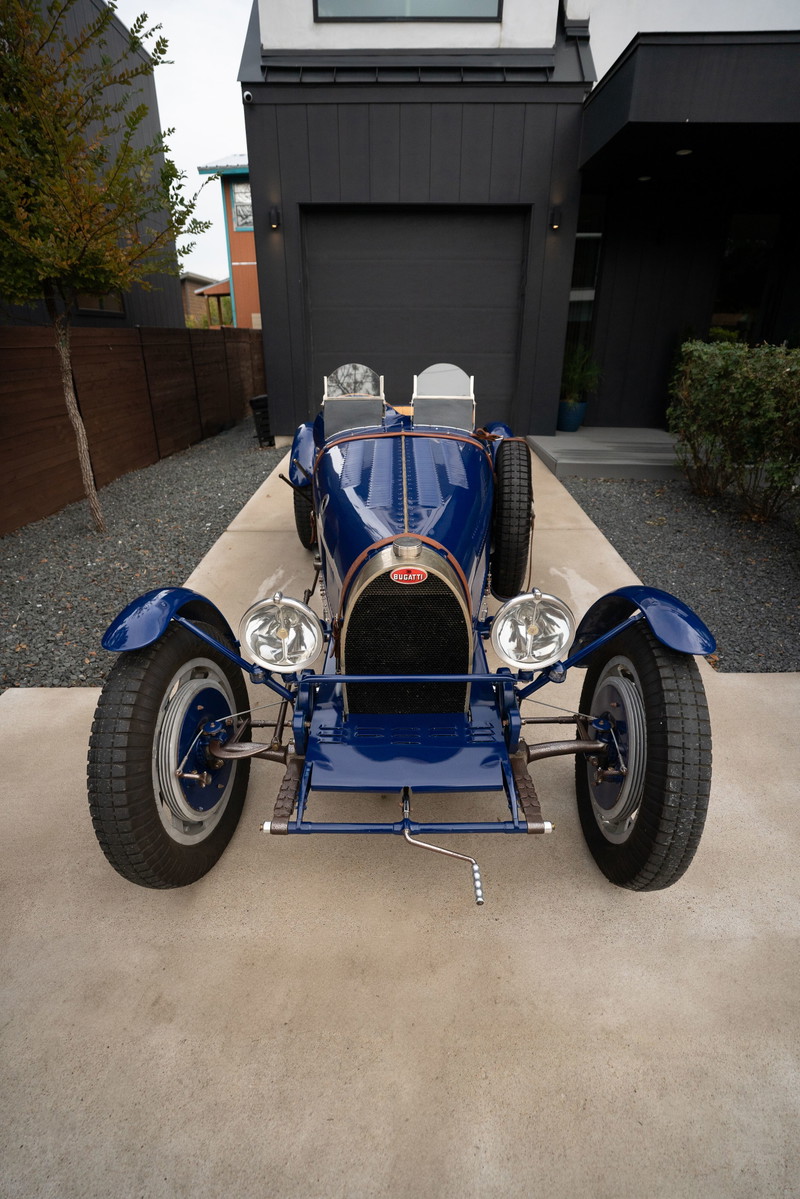 Front view of a blue 1927 Pur Sang Bugatti Type 35 with dual seats, spare tire, and spoked rims.