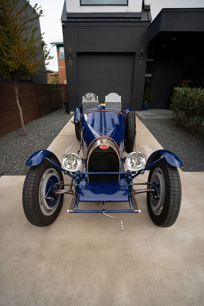 Front view of a blue 1927 Pur Sang Bugatti Type 35 with dual seats, spare tire, and spoked rims.
