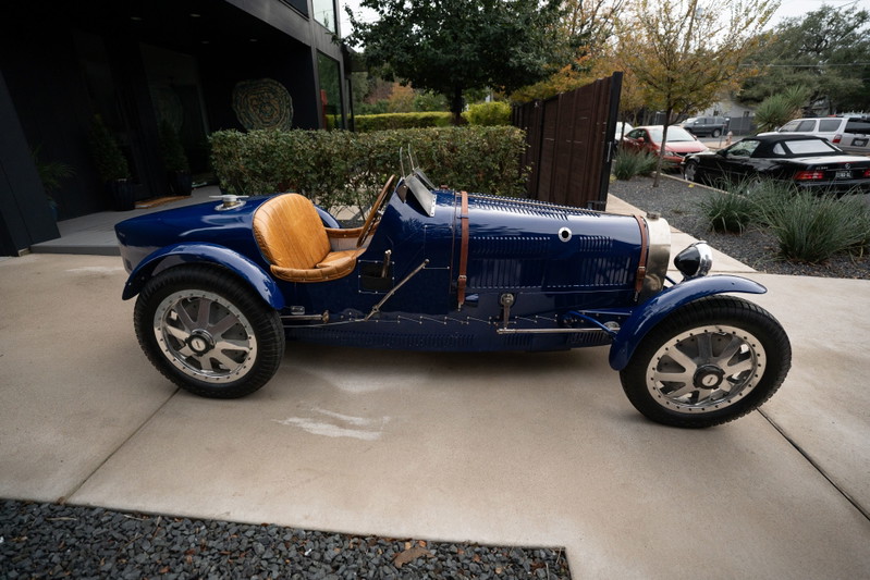 1927 Pur Sang Bugatti Type 35 in deep blue with tan leather seats and intricate silver rims.