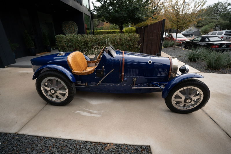 1927 Pur Sang Bugatti Type 35 in deep blue with tan leather seats and intricate silver rims.