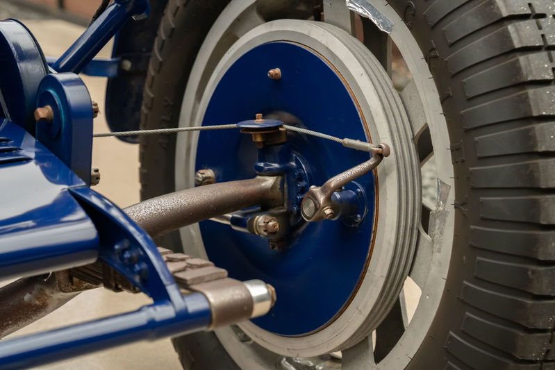 Close-up of a blue 1927 Bugatti Type 35 wheel, showing brake drum, suspension, and tire.