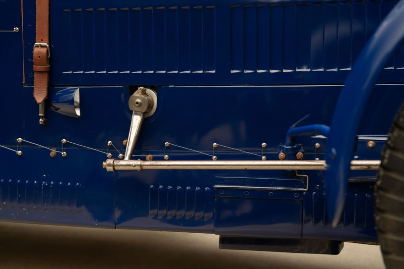 Close-up of the blue 1927 Bugatti Type 35 Pur Sang's side door with leather strap and chrome trim.