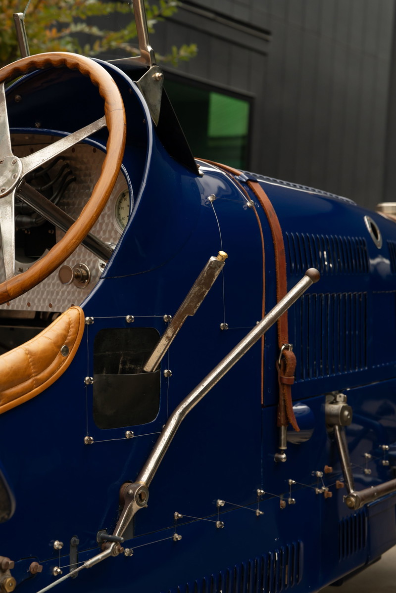 Close-up of a blue 1927 Bugatti Type 35, showing leather trim, wooden steering wheel, and metal levers.
