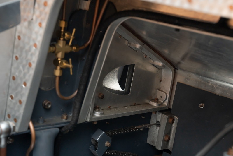 Vintage Bugatti Type 35 dash detail with brass fuel valves and raw aluminum trim.