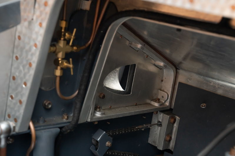 Vintage Bugatti Type 35 dash detail with brass fuel valves and raw aluminum trim.