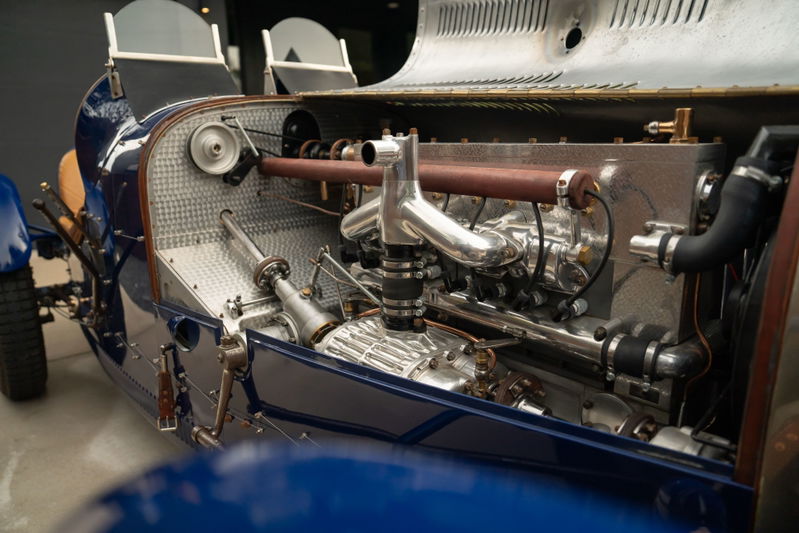 Detailed view of the engine bay of a blue 1927 Pur Sang Bugatti Type 35 race car, showcasing its mechanical components.