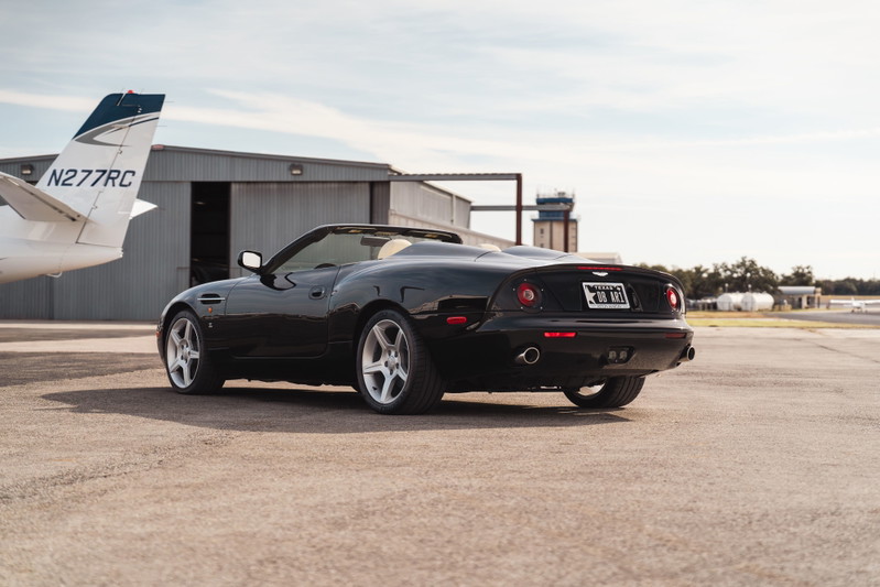 2003 black Aston Martin DBAR1 Zagato convertible with silver rims on an airport tarmac.
