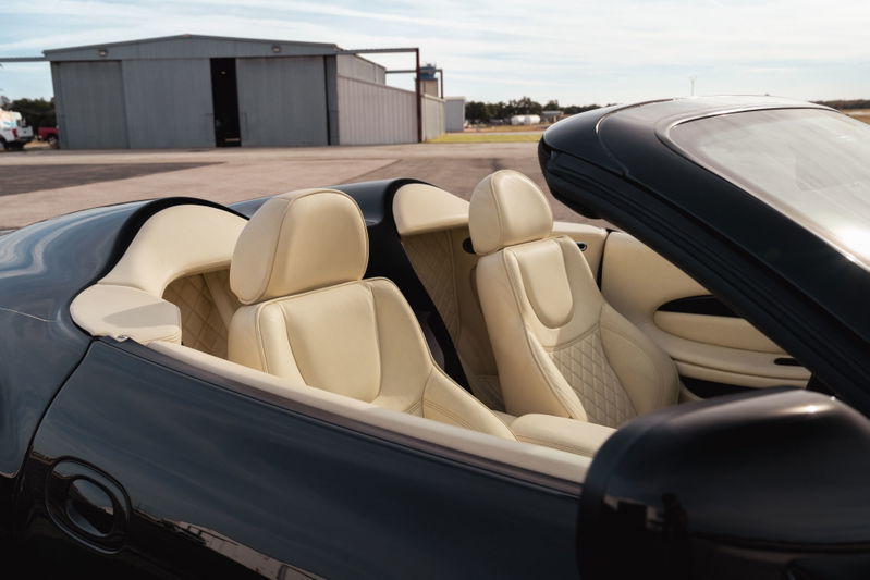 Black 2003 Aston Martin DB AR1 Zagato convertible interior with cream leather seats and diamond stitching.