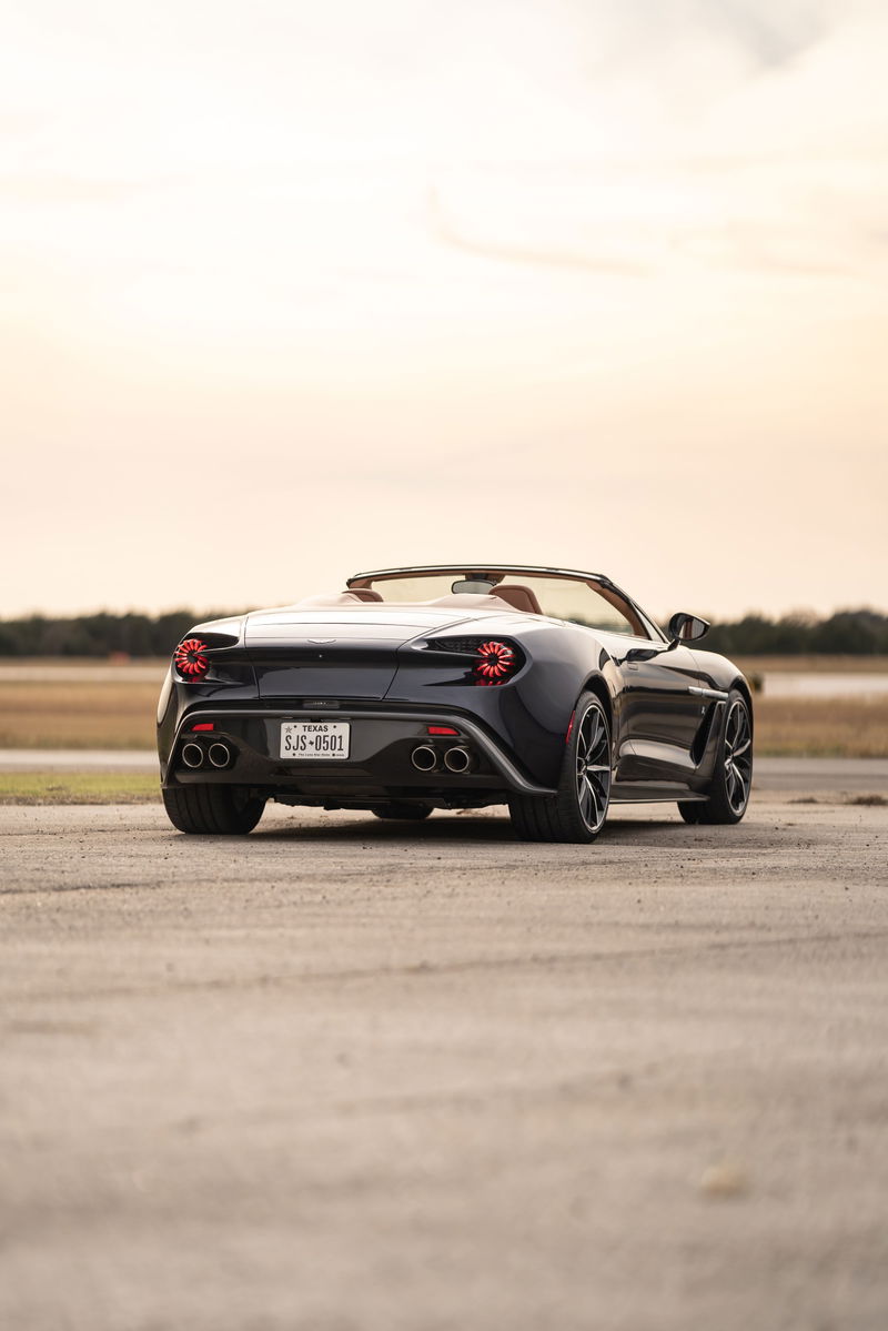 Rear view of a dark blue 2018 Aston Martin Vanquish Zagato convertible with quad exhaust tips and unique taillights.