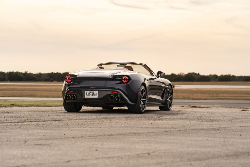 Rear view of a dark blue 2018 Aston Martin Vanquish Zagato convertible with quad exhaust and unique wheels.