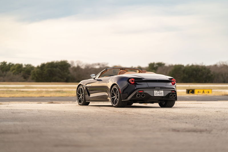 Rear view of a dark blue 2018 Aston Martin Vanquish Zagato convertible with tan interior and multi-spoke rims.
