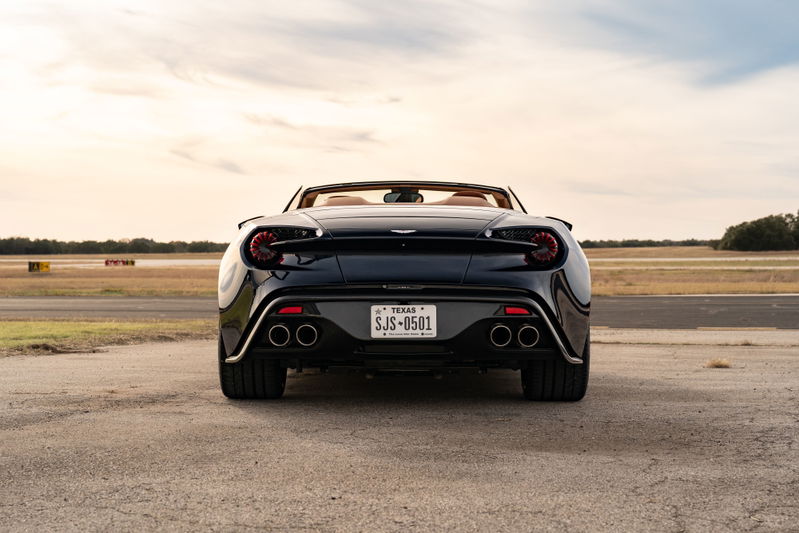 Rear view of a dark blue 2018 Aston Martin Vanquish Zagato convertible with dual exhaust pipes.