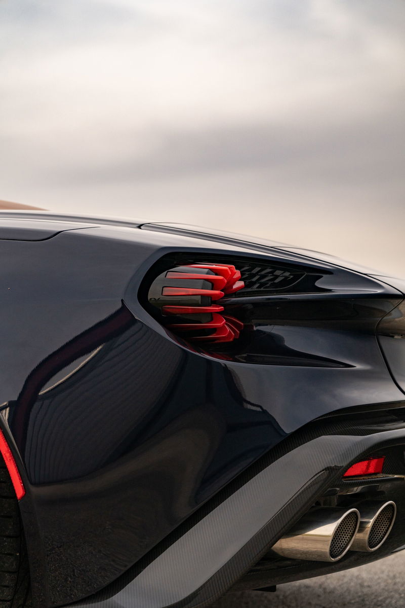 Rear detail of a dark blue Aston Martin Vanquish Zagato, featuring red taillights and quad exhaust tips.