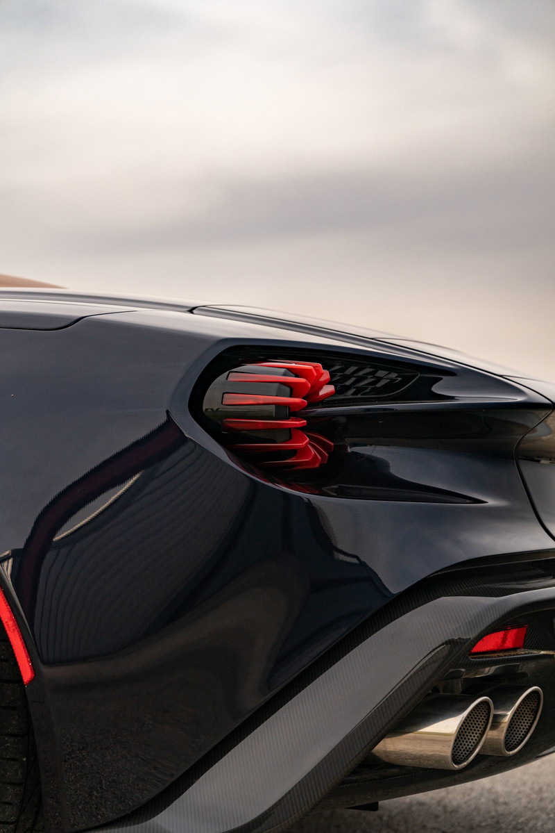 Rear detail of a dark blue Aston Martin Vanquish Zagato, featuring red taillights and quad exhaust tips.