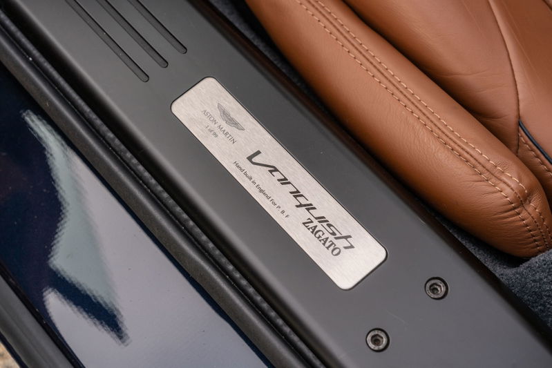 Aston Martin Vanquish Zagato door sill trim plate with brown leather seat.