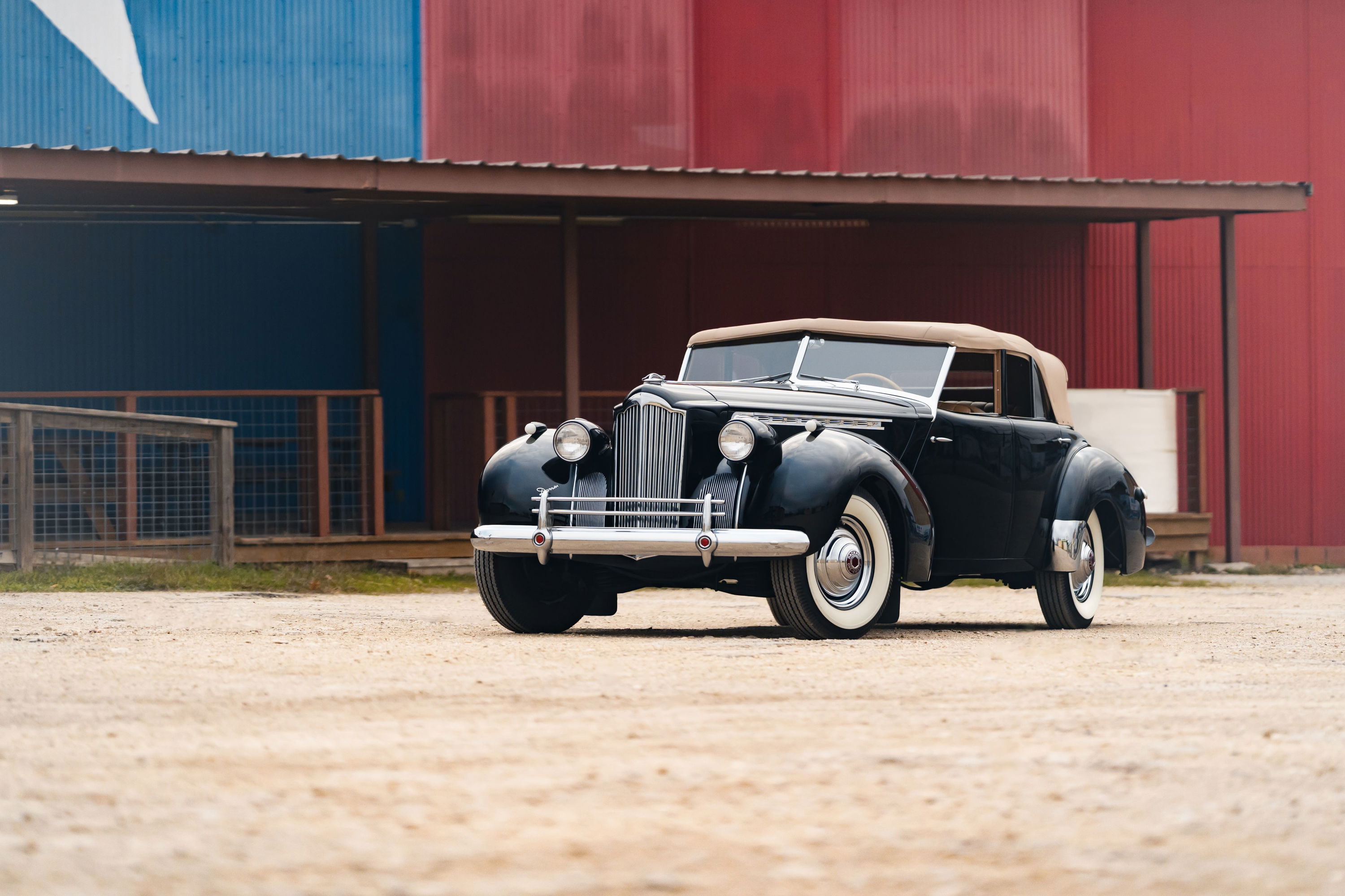 Black 1940 Packard Super Eight convertible with tan top and whitewall tires.