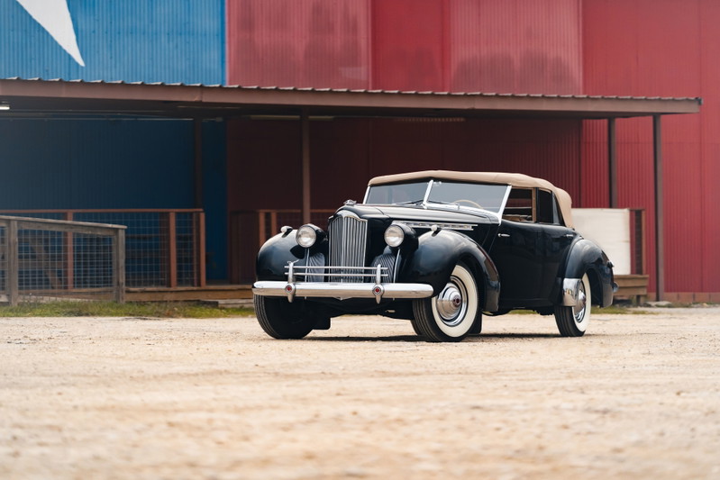 Black 1940 Packard Super Eight convertible with tan top and whitewall tires.