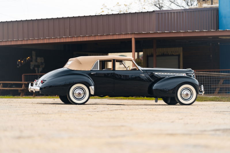 1940 Packard Super Eight One Eighty convertible in black with tan top and whitewall tires.