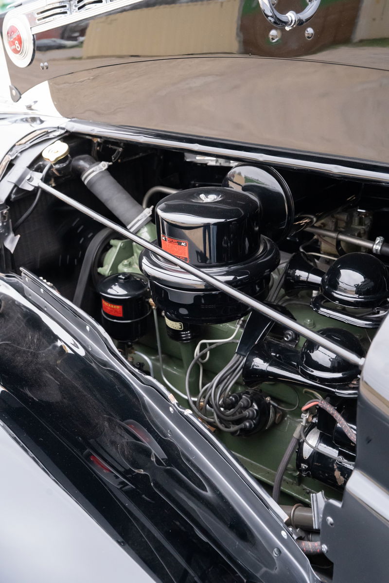 Close-up of a black 1940 Packard Super Eight's inline-eight engine, featuring a large air cleaner.