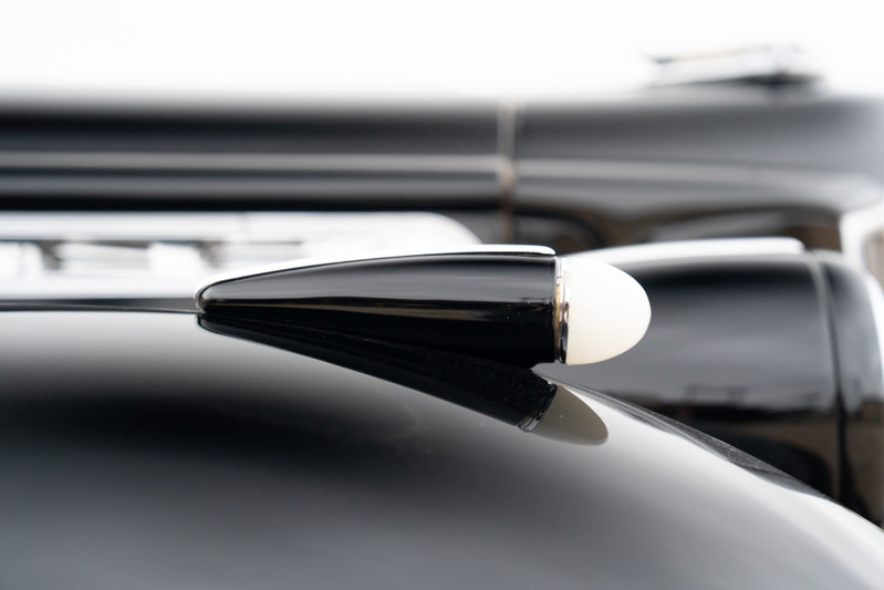 Close-up of a black 1940 Packard Super Eight One-Eighty's illuminated antenna.