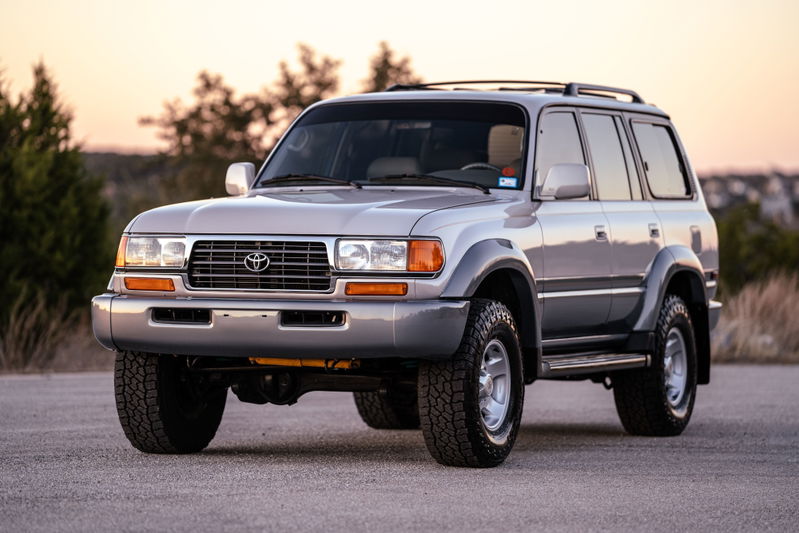 Silver 1997 Toyota Land Cruiser FJZ80 with grey fender flares, roof rack, and all-terrain tires.