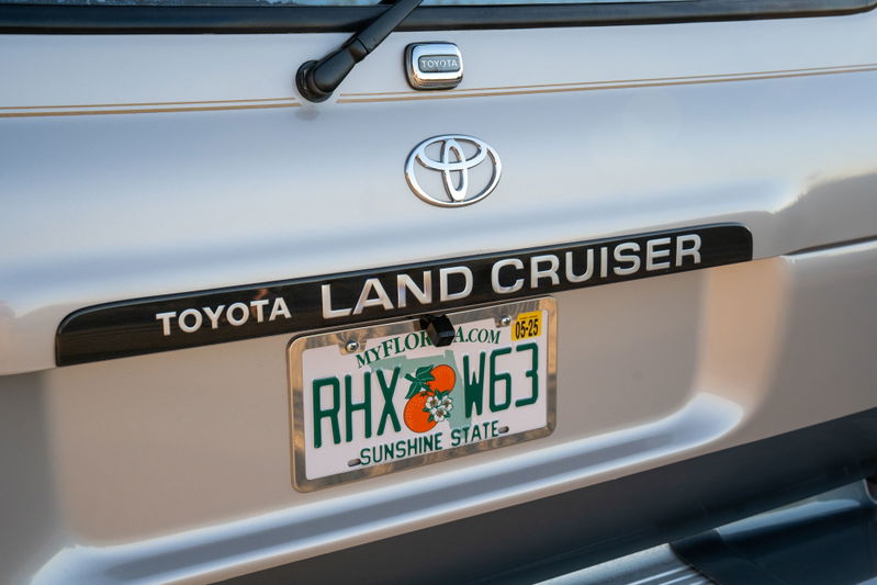 Silver 1997 Toyota Land Cruiser FJ80 rear with "LAND CRUISER" trim and Florida license plate.