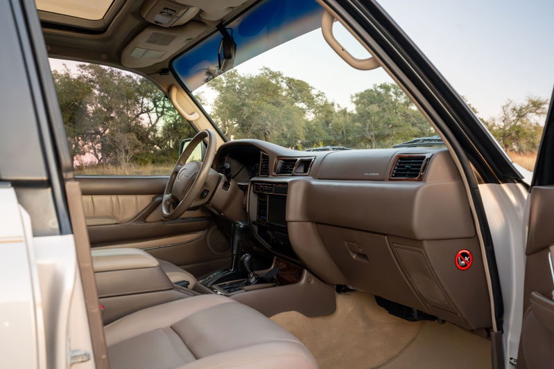 Interior view of a 1997 Toyota Land Cruiser FZJ80 in Desert Dune Metallic, showing leather seats & dashboard.