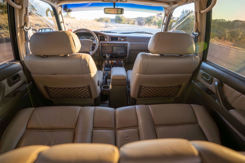 Interior shot of a 1997 Toyota Land Cruiser in Desert Dune Metallic, showcasing tan leather seats and dashboard trim.