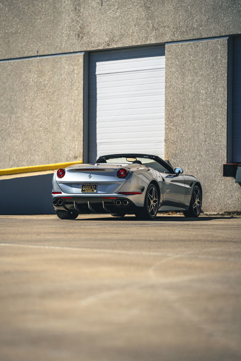 Rear view of a silver 2016 Ferrari California T convertible with black rims.