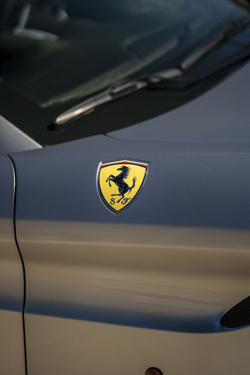 Close-up of a Ferrari Scuderia emblem on the fender of a silver 2016 Ferrari California T.