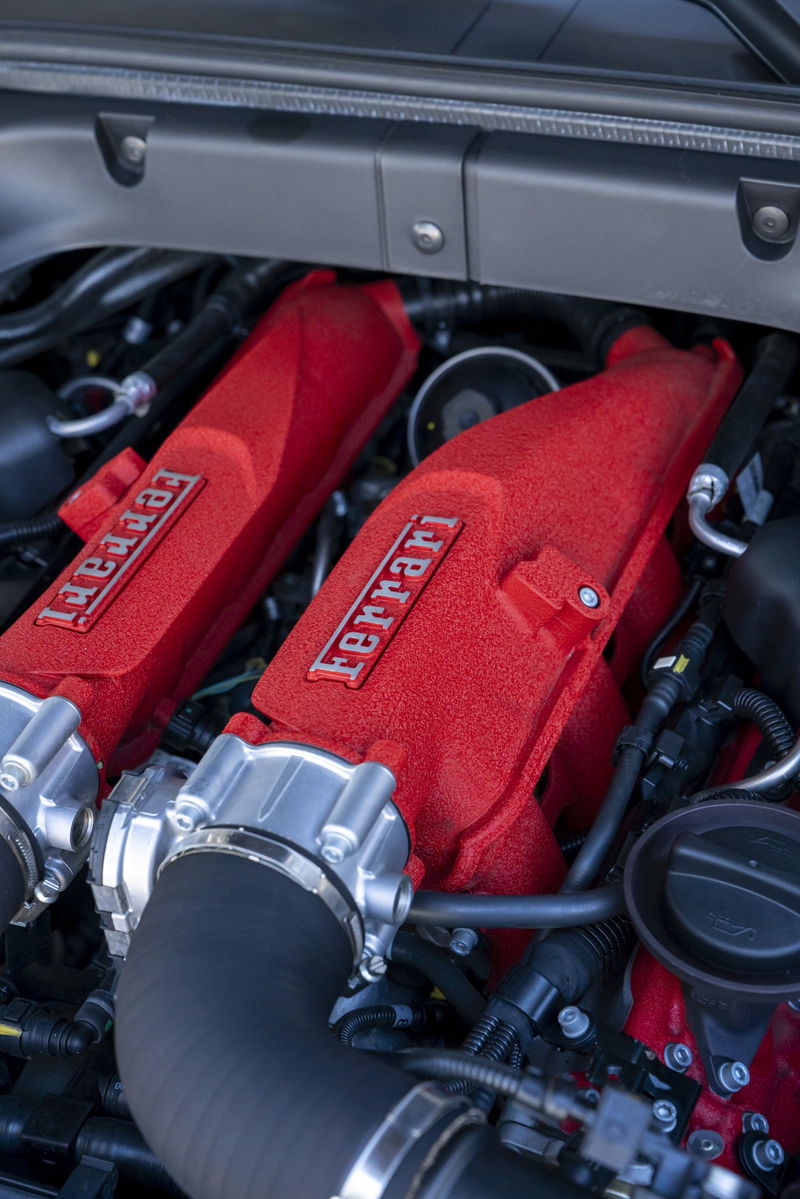 Close-up of a red Ferrari engine intake manifold with Ferrari badging.