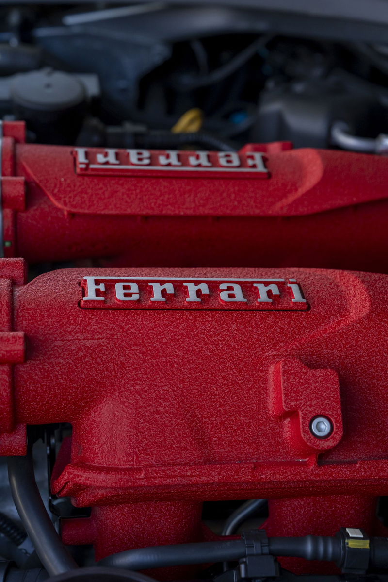 Close-up of a red Ferrari engine intake manifold with silver "Ferrari" badging.
