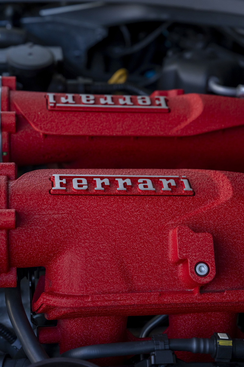 Close-up of a red Ferrari engine intake manifold with silver "Ferrari" badging.