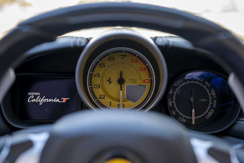 Close-up of a 2016 Ferrari California T dashboard with yellow tachometer and mph speedometer.